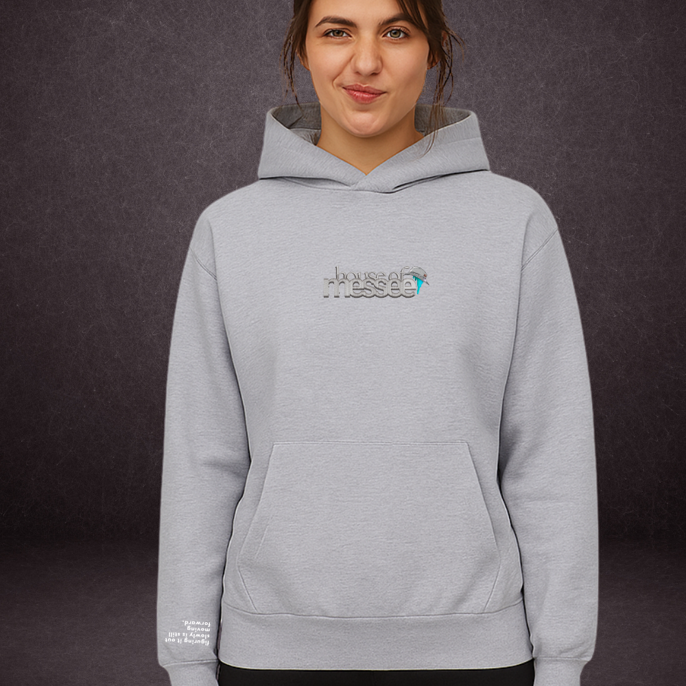 Person wearing a gray hoodie with a logo on a dark background