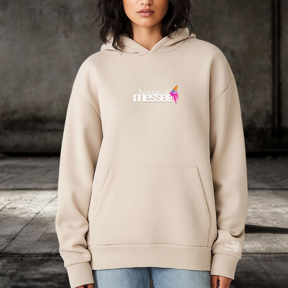 Person wearing a beige hoodie with a logo and text on a dark background