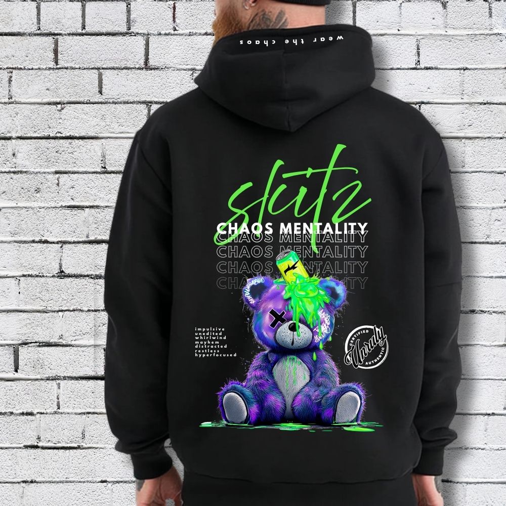 Person wearing a black hoodie with a colorful bear graphic and text on the back against a white brick wall.